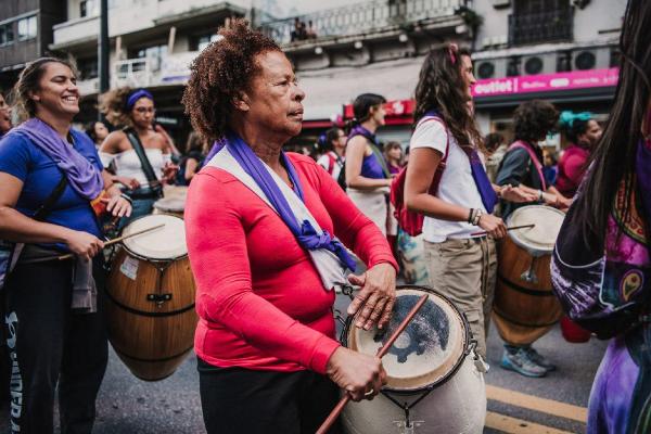 Comparsa de mujeres "Melaza", varias mujeres caminando y tocando el tambor por la calle.
