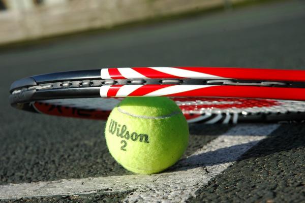 Raqueta sobre pelota de tenis apoyada en el suelo