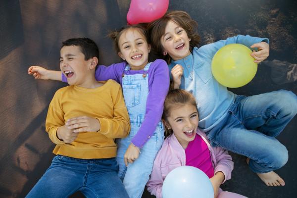 Niños riendo juntos, acostdos en el suelo.