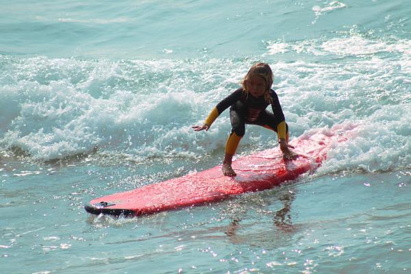 Niño surfeando una ola pequeña con una tabla de aprendizaje