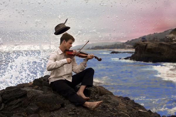 Hombre tocando el violín junto al mar