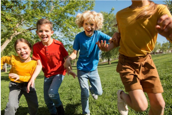 Niños tomados de las manos corriendo por un campo verde 