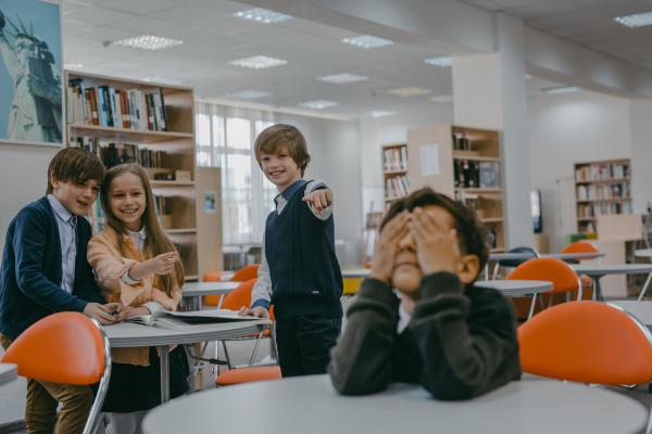 Niños riéndose se forma burlona y señalando a otro niño