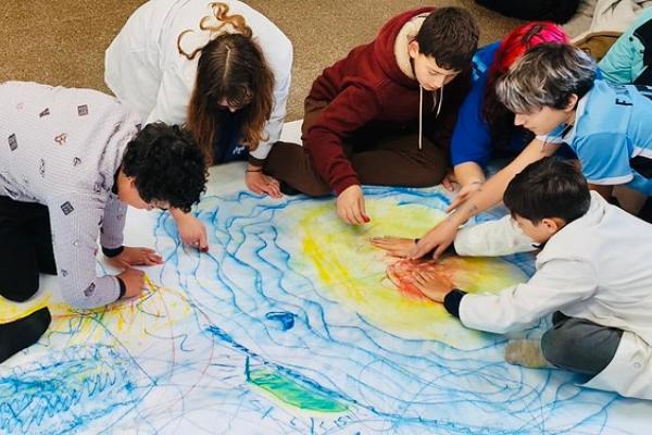 Niños pintando en un papel grande en el piso