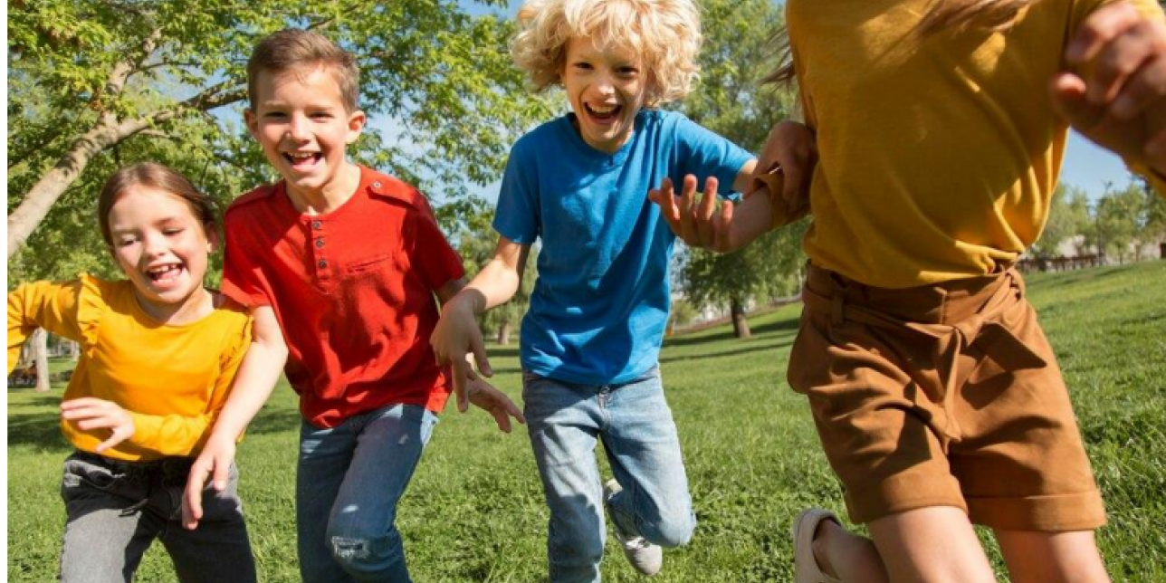 Niños tomados de las manos corriendo por un campo verde 