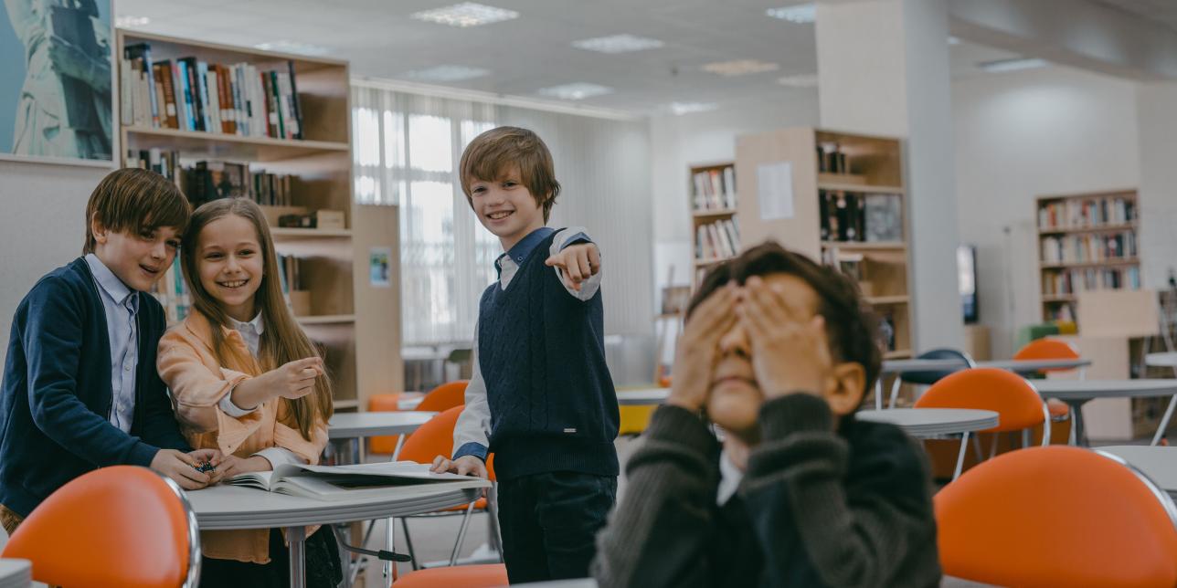Niños riéndose se forma burlona y señalando a otro niño