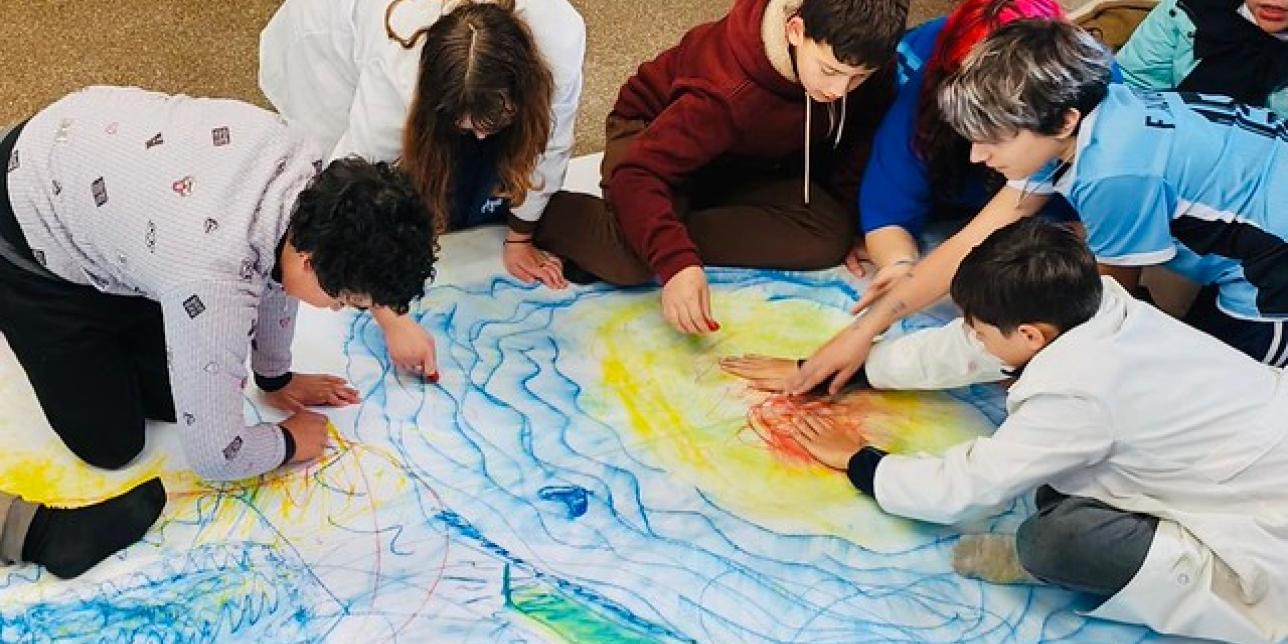 Niños pintando en un papel grande en el piso